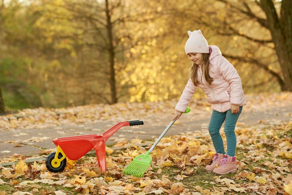 Child raking leaves for a spring clean up fundraiser