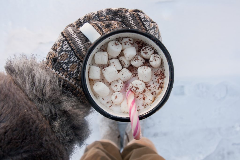 Person holding hot chocolate with a gloved hand at a fundraiser