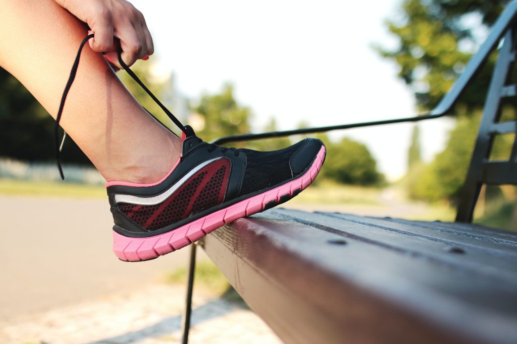 Person tying a running shoe to participate in a sport fundraiser