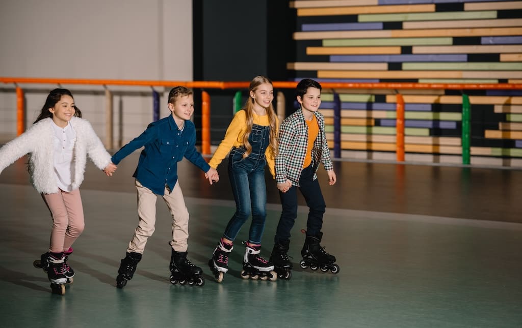 Four school kids rollerblading at a roller rink