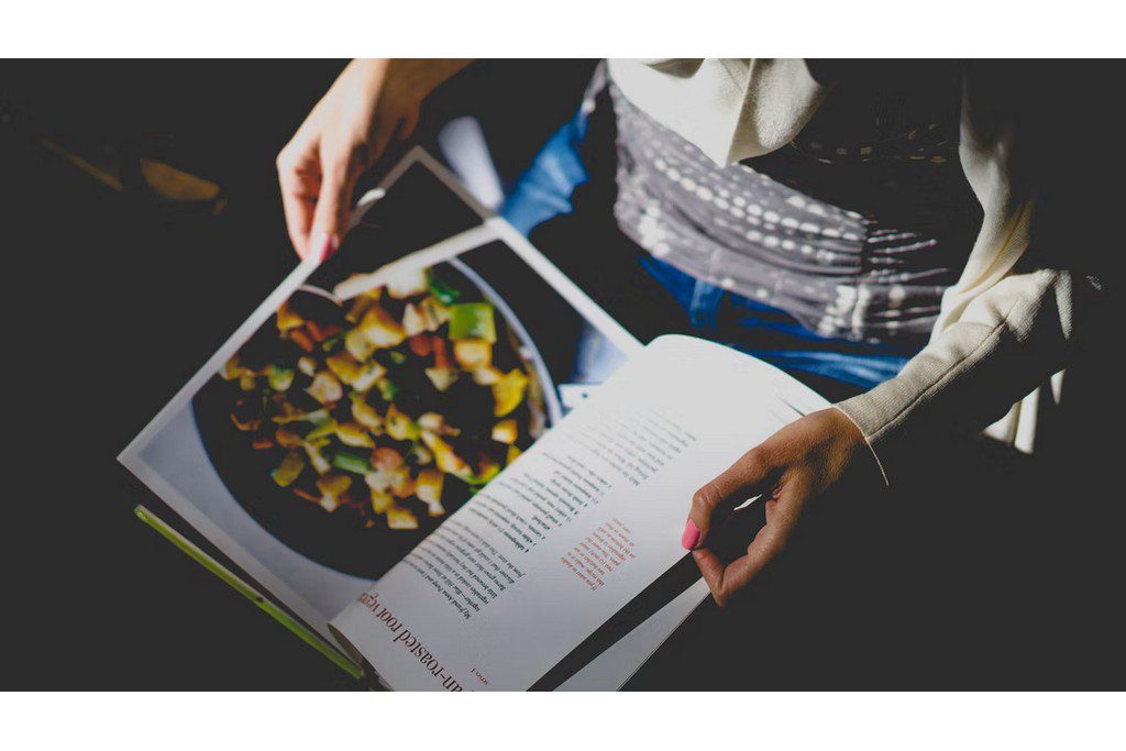 A person holding a cooking book open in their lap