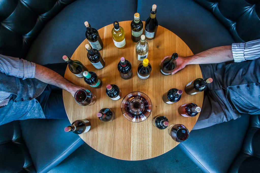 A top-down view of wine bottles on a round wooden table