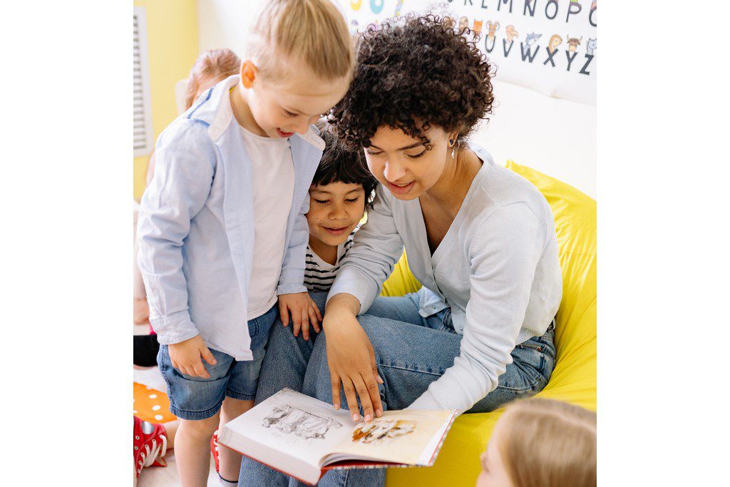 teacher reading a book to several children at school