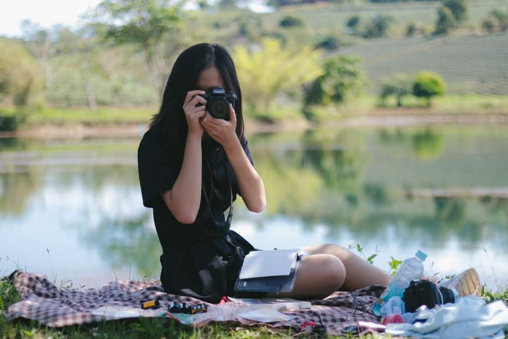An woman taking a photo by a lake