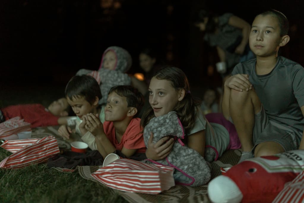 kids in a field watching a movie