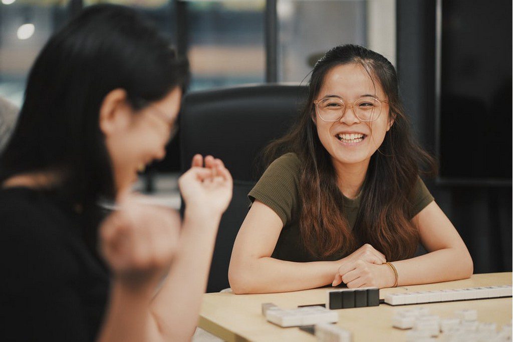 Two women laughing with each other at a desk