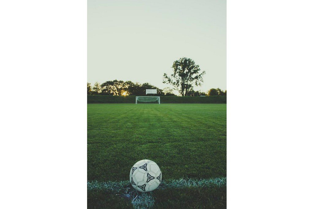 A soccer ball on a green field with a goal post soccer ball on a soccer field
