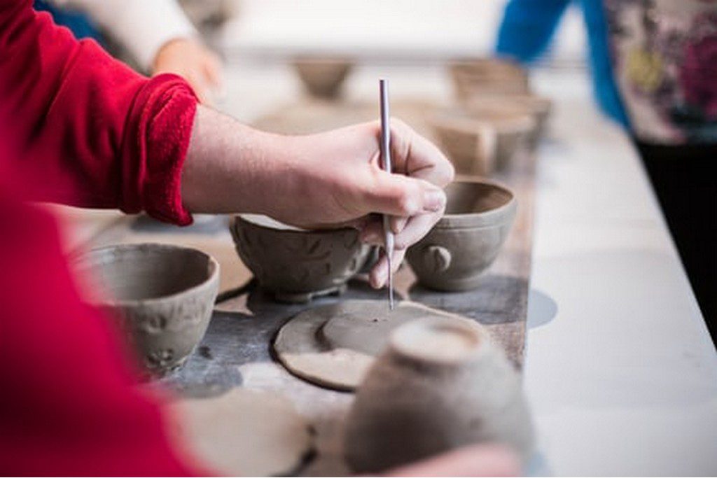 person carving pottery