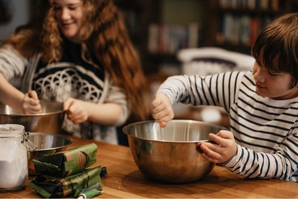 two kids making food in a bowl together