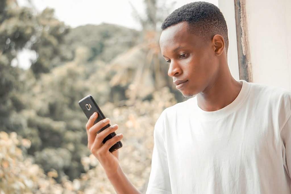 A man looking at a phone by a window