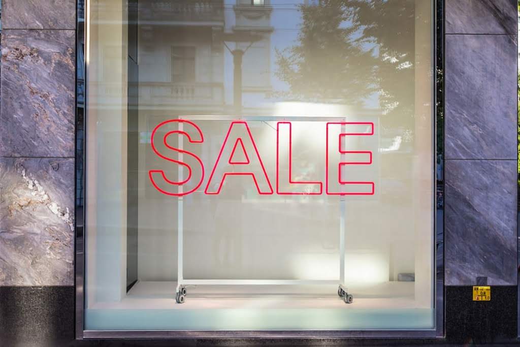 A red SALE sign in a window sale sign at a store