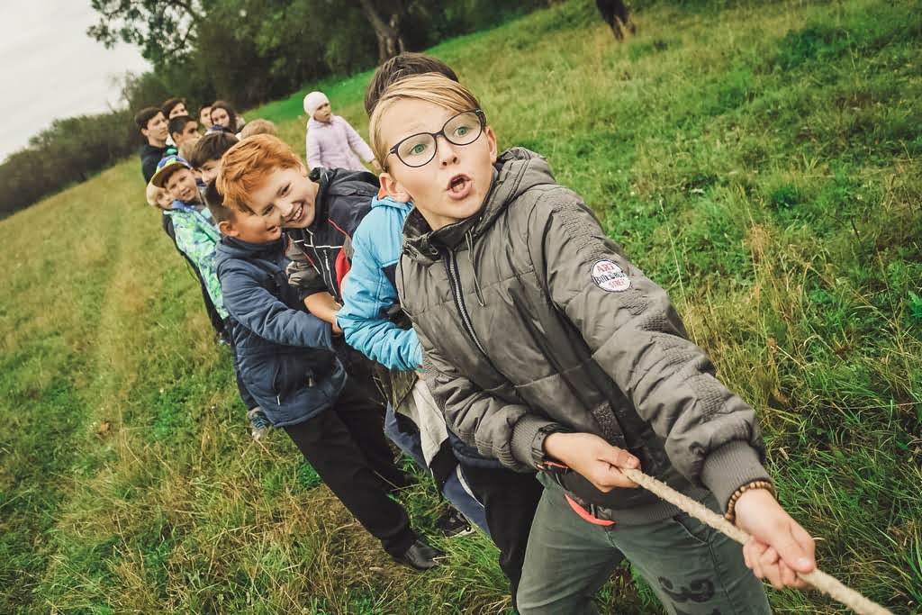 Caucasian children playing tug of war on a field kids playing tug of war