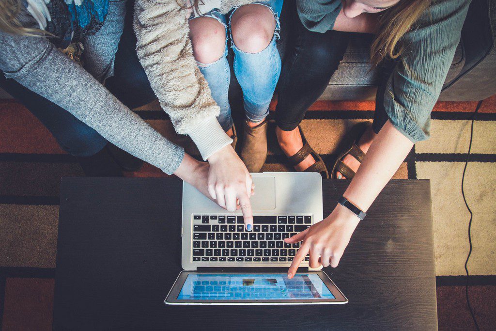 3 people pointing at a laptop screen kids pointing at a laptop