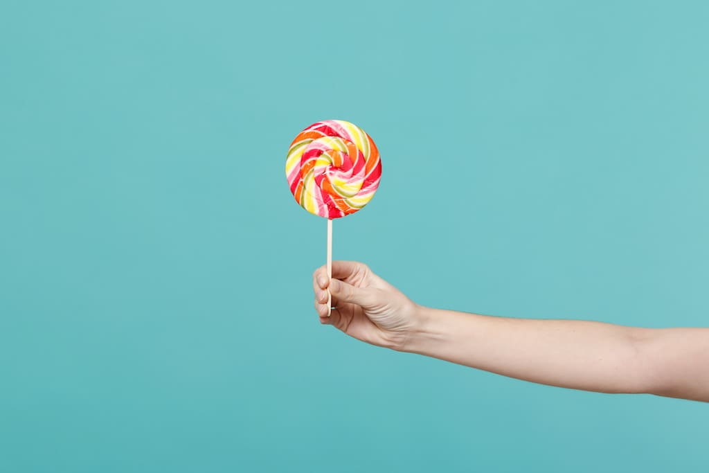 Person Reaching Out Holding A Lollipop