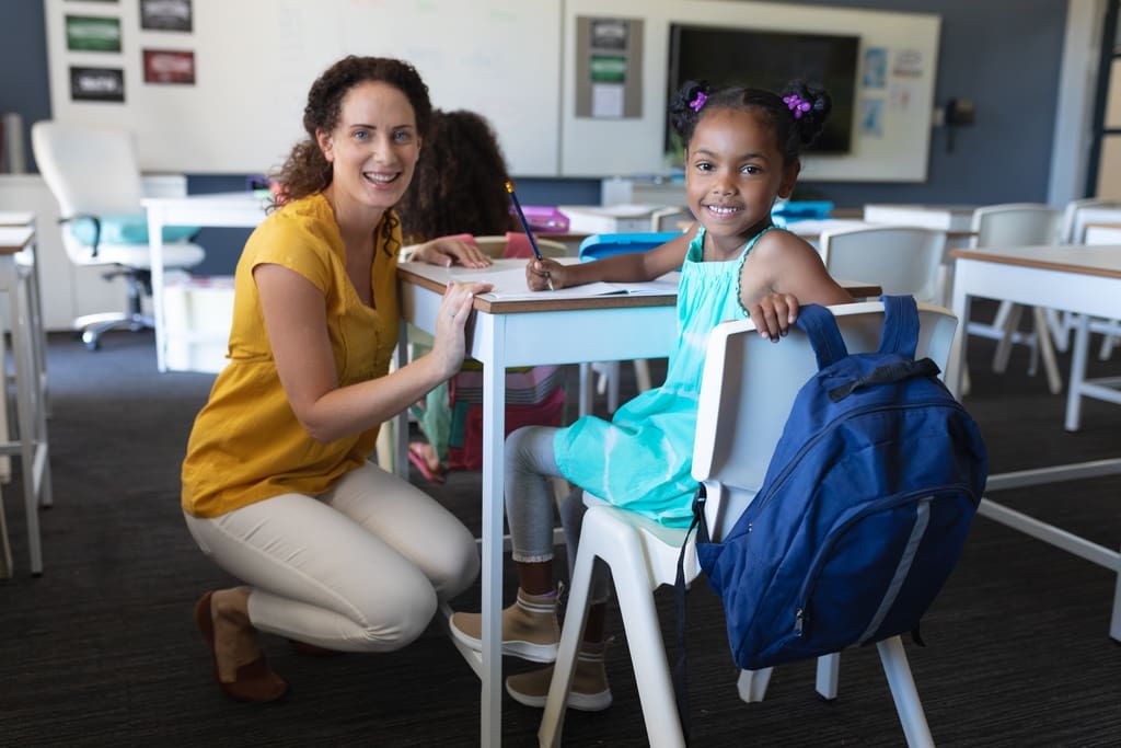 Teacher and elementary school student smiling to represent positive change accomplished via Giving Tuesday