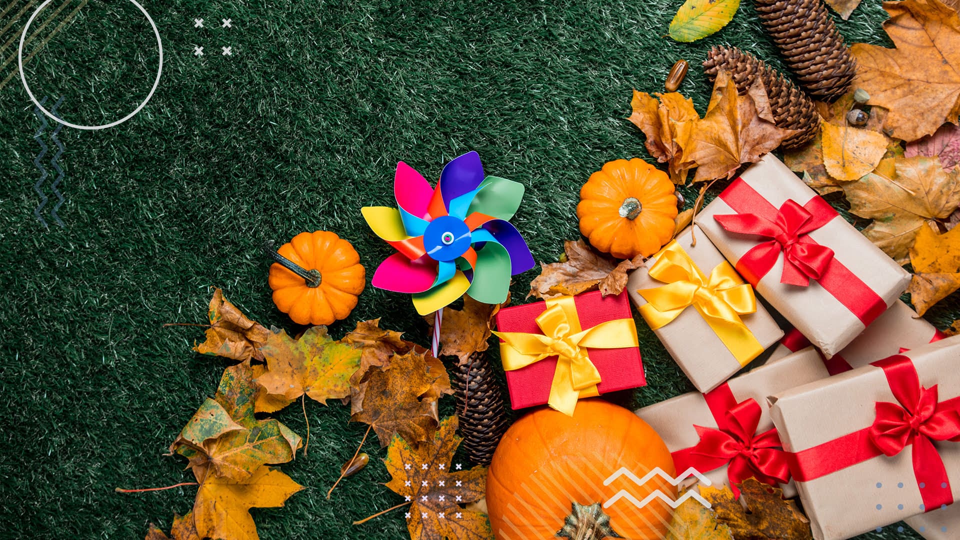 Pumpkins and gifts laying on green grass with yellow leaves surrounding them