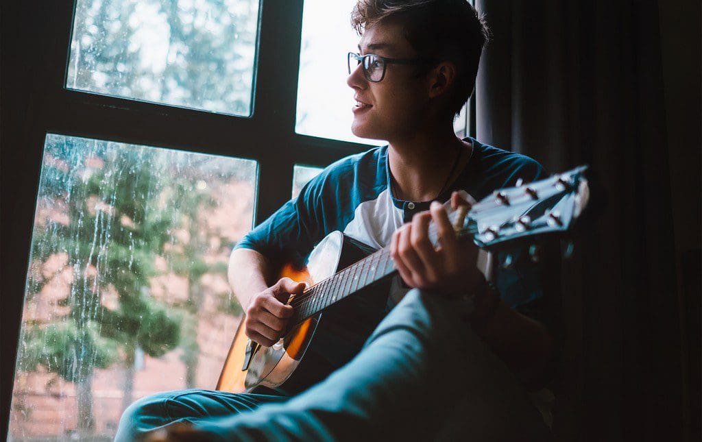 A teen practicing singing and playing guitar before a sing-a-thon