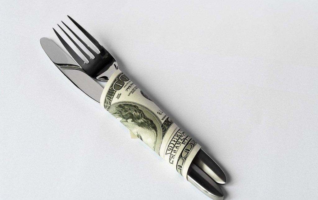 Fork and knife wrapped in dollar bill to symbolize fundraising dinner
