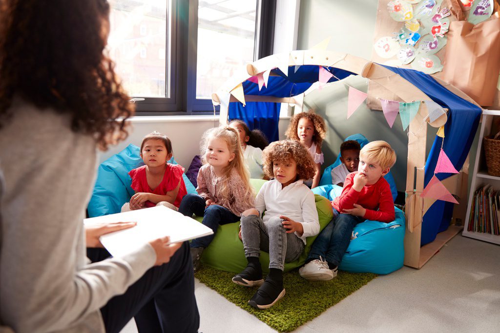 Teacher reading to students in reading corner of elementary school classroom