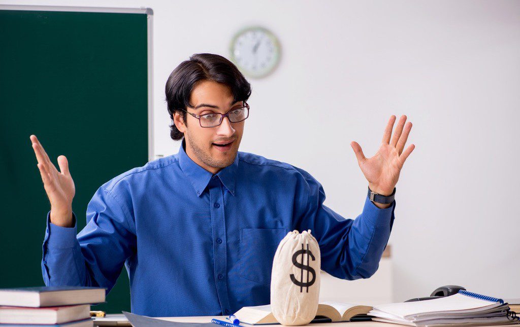 Teacher with bag of money on desk to symbolize access to funds raised through PTA or PTO