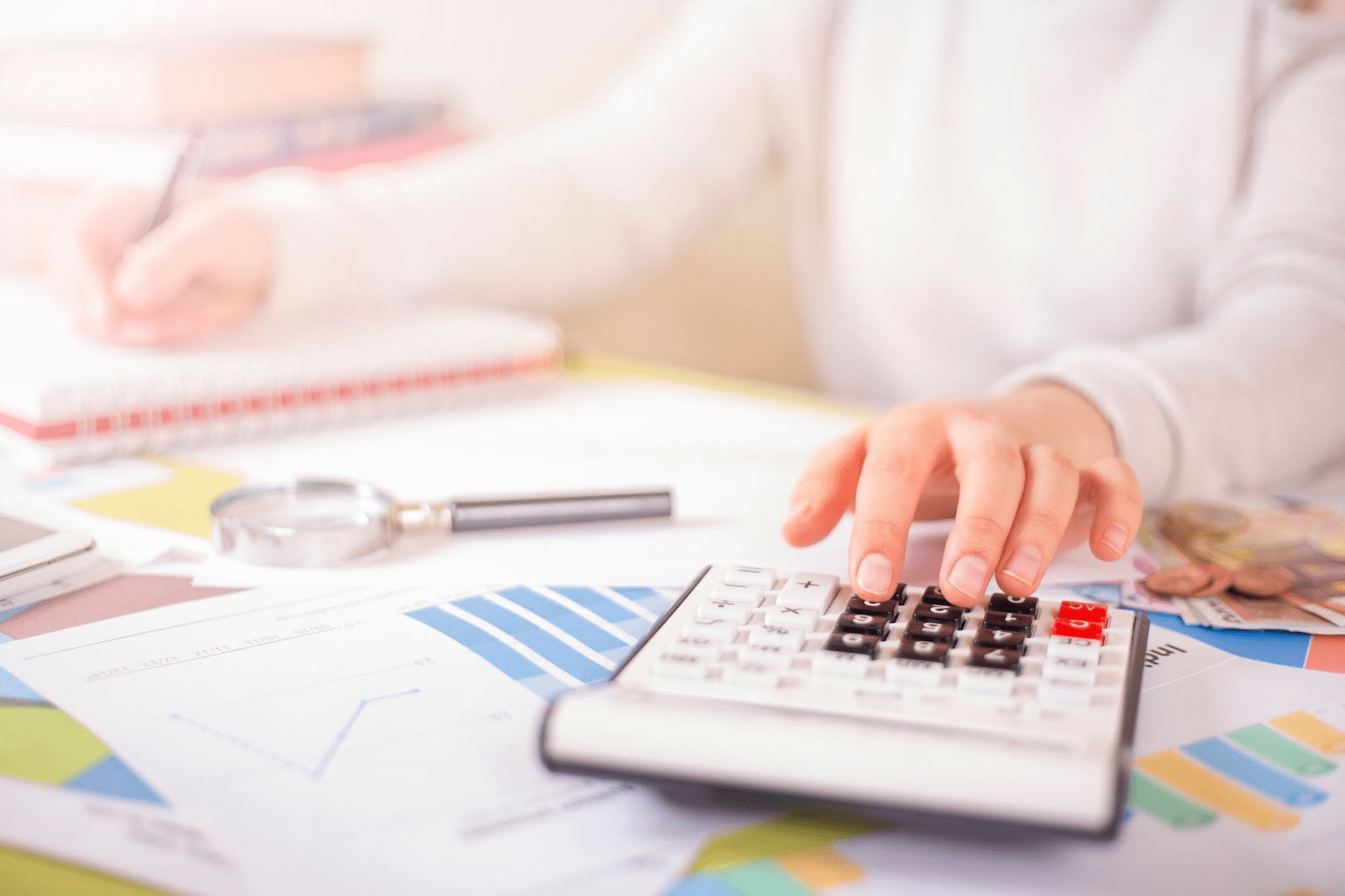 PTA treasurer developing annual budget with calculator and printouts of financial data