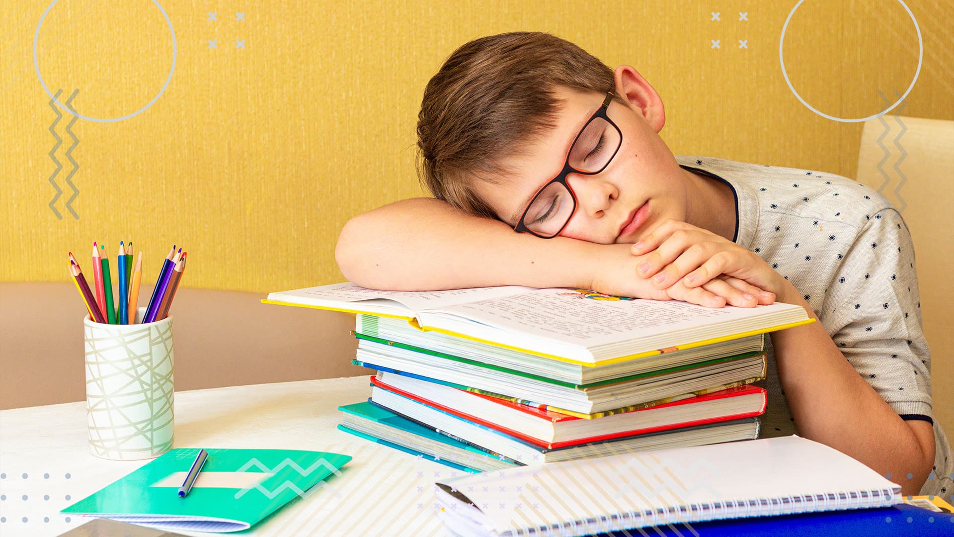 Young boy sleeping with head on school textbook in classroom