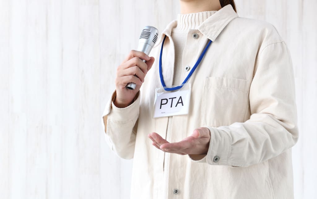 Woman wearing a PTA badge talking into a microphone