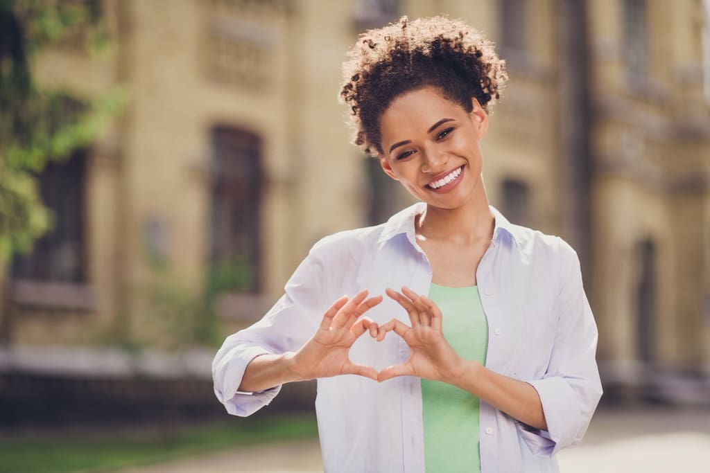 Young African American woman making heart with hands to symbolize February school fundraising opportunities