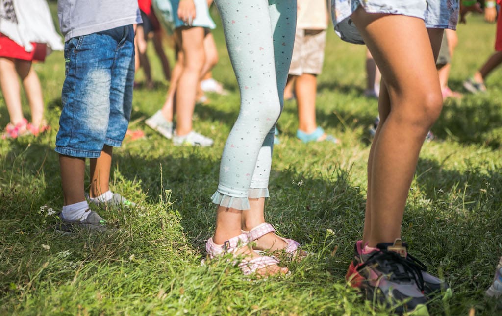 The legs of many children lined up for an activity