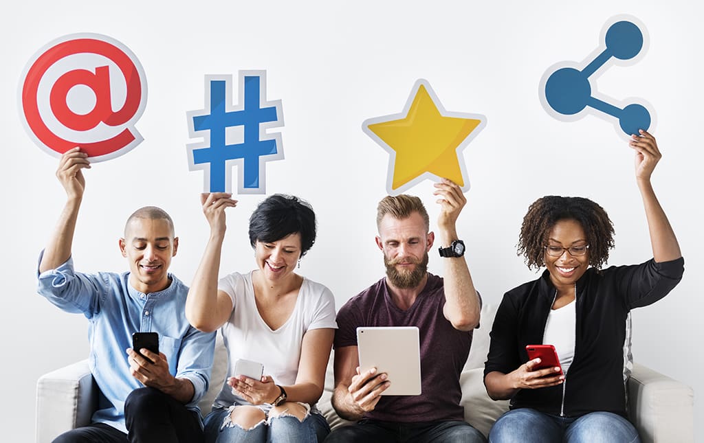 Alumni of various age ranges hold up social media icons